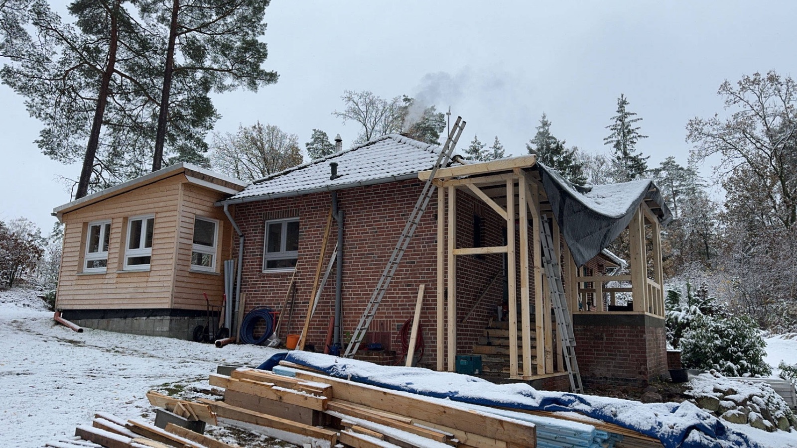 Anbau in der Bauphase mit Holzständerwerk am Backsteinhaus, erster Schnee liegt